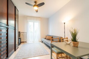 Ein modernes Wohnzimmer mit einer Couch, einem Esstisch, einem Deckenventilator und einer Heizung.