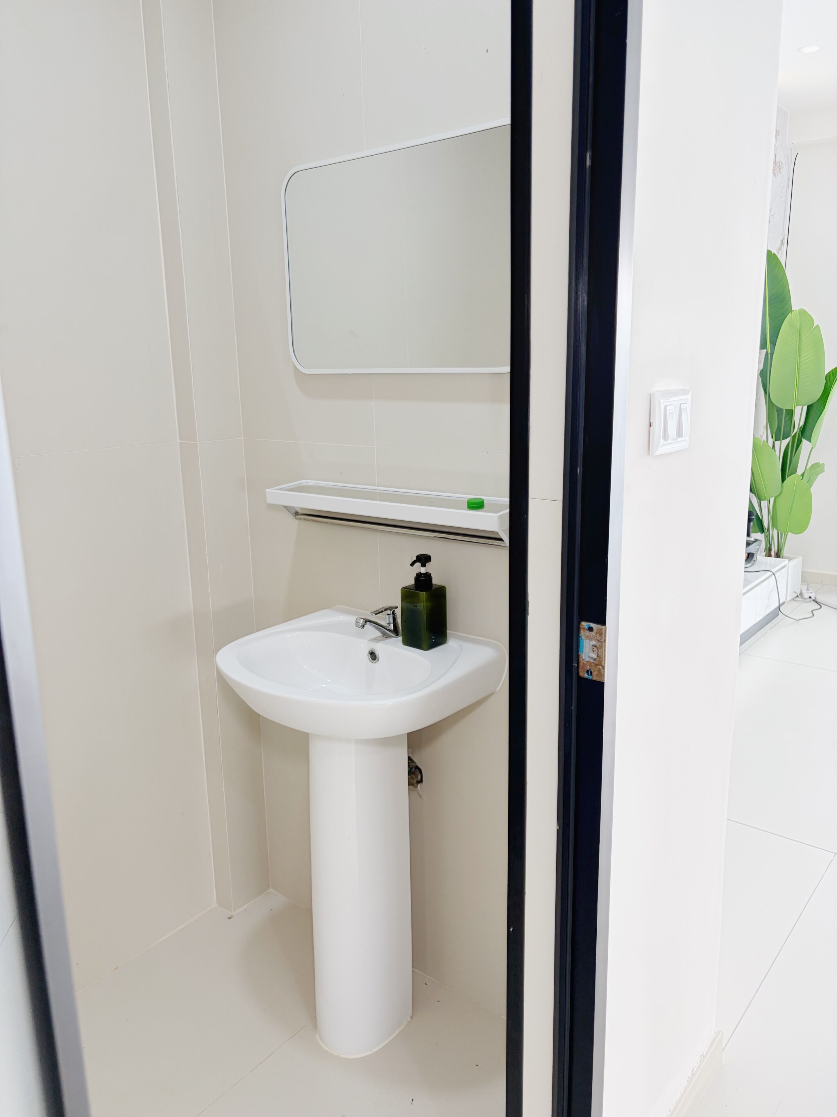 A bathroom with a white sink, a mirror, and a green soap dispenser.