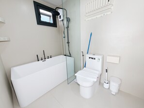 Et moderne badeværelse med badekar, toilet og bruser.