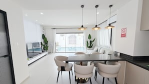 A modern kitchen with a dining area, white cabinetry, and pendant lighting. - POOL Villa KTV BBQ Friends Thepprasit (Muang Pattaya)