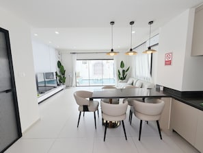 A modern kitchen with a dining area, white cabinetry, and pendant lighting. - POOL Villa KTV BBQ Friends Thepprasit (Muang Pattaya)