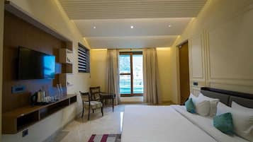 A hotel room with a large bed, a flat-screen TV, a seating area, and a window with curtains.