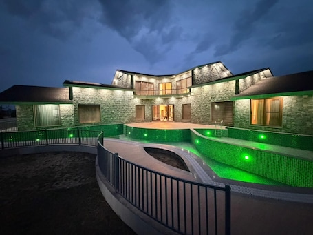 A modern house with a swimming pool, stone exterior, and a well-lit entrance.. Rosewood Manor BNB