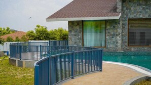 A modern house with a swimming pool, stone exterior, and a fenced patio area. - Rosewood Manor BNB (Alwar)