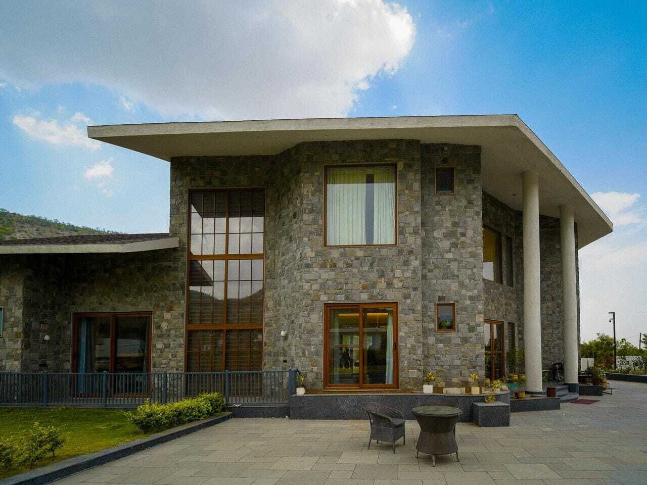 A stone building with large windows and a covered patio area.