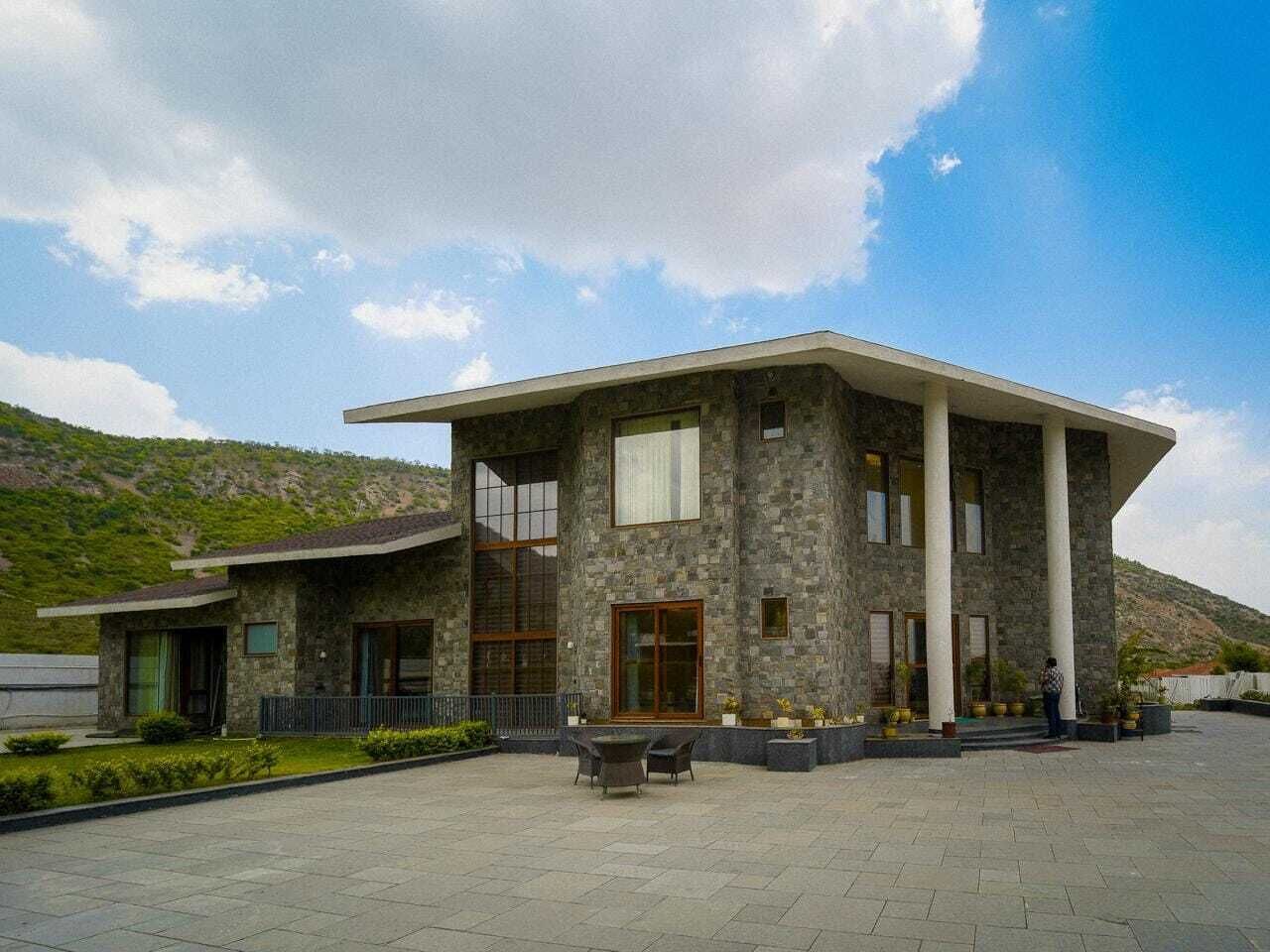 A modern two-story house with a stone facade, large windows, and a spacious front porch.