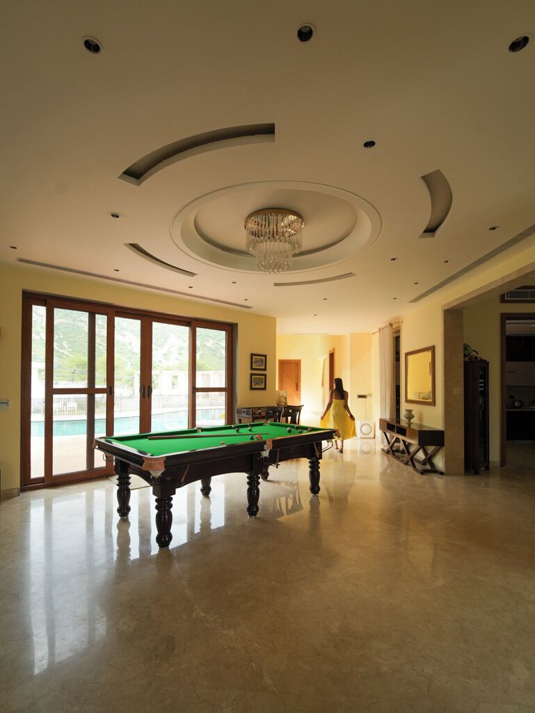 Une pièce spacieuse équipée d’une table de billard, d’un lustre et d’une grande fenêtre offrant une vue imprenable.