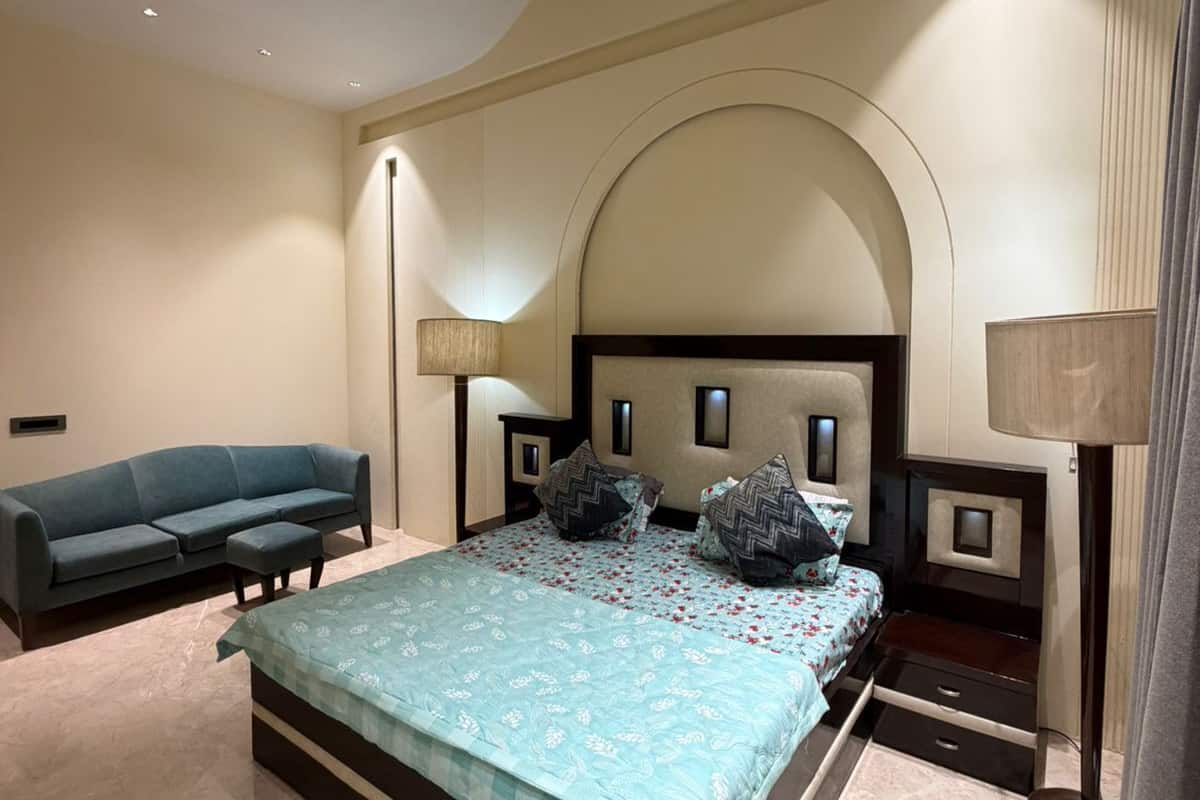 A bedroom with a large bed, a sofa, and two bedside tables with lamps.