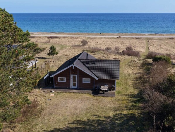 A single-story house with a tiled roof, a front door, and a small porch with outdoor seating. - 4 Star Holiday Home in Ebeltoft (Ebeltoft)