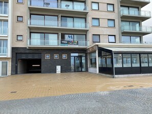 Ein mehrstöckiges Gebäude mit Eingangsbereich auf Erdgeschossniveau, einer Glasfassade und einem Schild mit der Aufschrift 'Motel Morti Del Sol'.