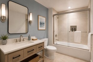 Un baño moderno con un espejo grande, un lavabo con dos grifos, un inodoro y una zona de ducha con mampara de vidrio.