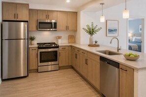 Una cocina moderna con electrodomésticos de acero inoxidable, armarios de madera, lavavajillas y un lavamanos.