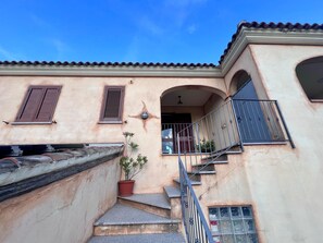 Ein Gebäude mit Treppe, Blumentopf und Balkon.