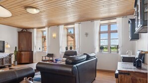 A spacious living room with a leather sofa, wooden table, and a television. - 5 Star Holiday Home in Tonder (Tonder)