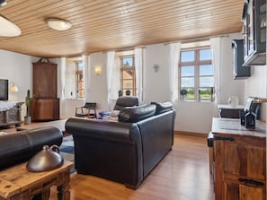 Ett rymligt vardagsrum med en soffa i läder, ett träbord och en tv.