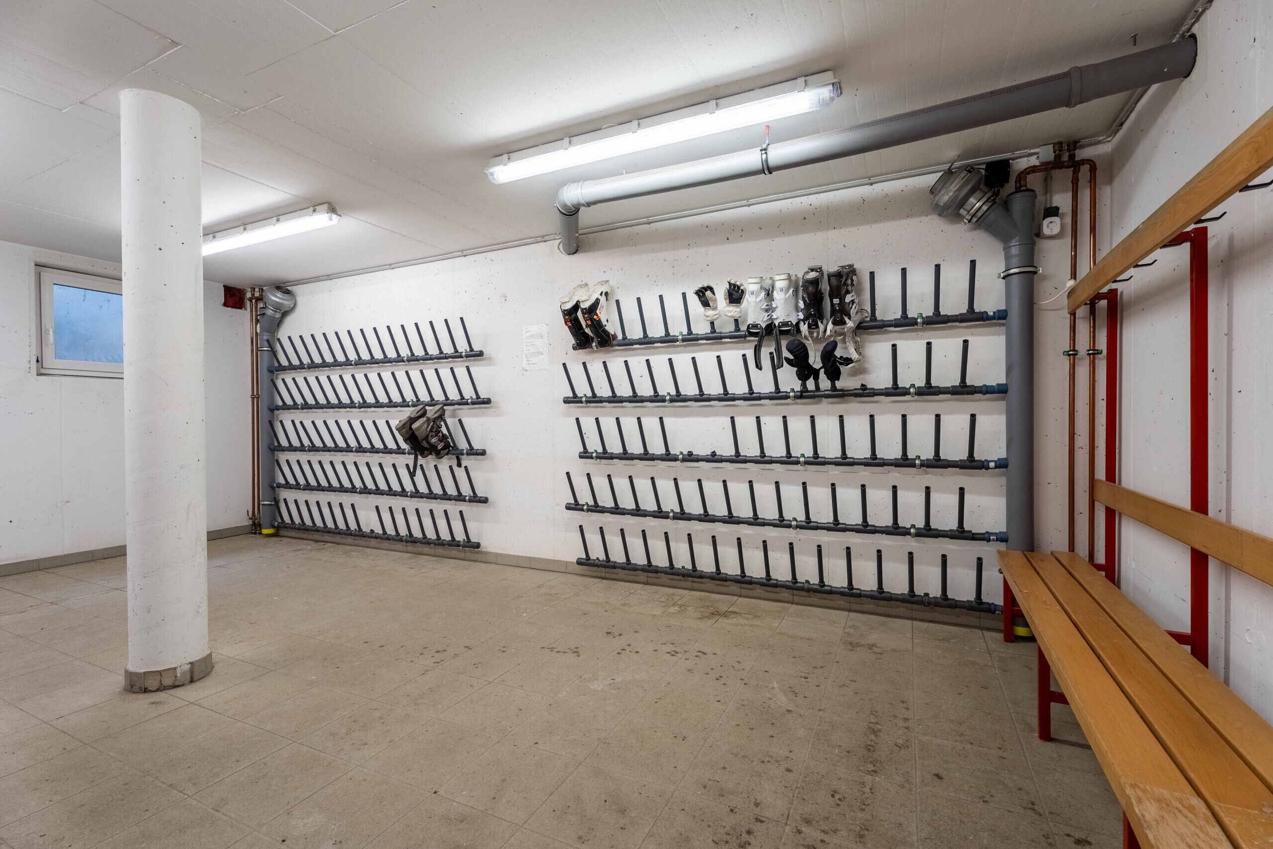 A storage room with rows of pipes and valves on shelves, a wooden bench, and a pillar.
