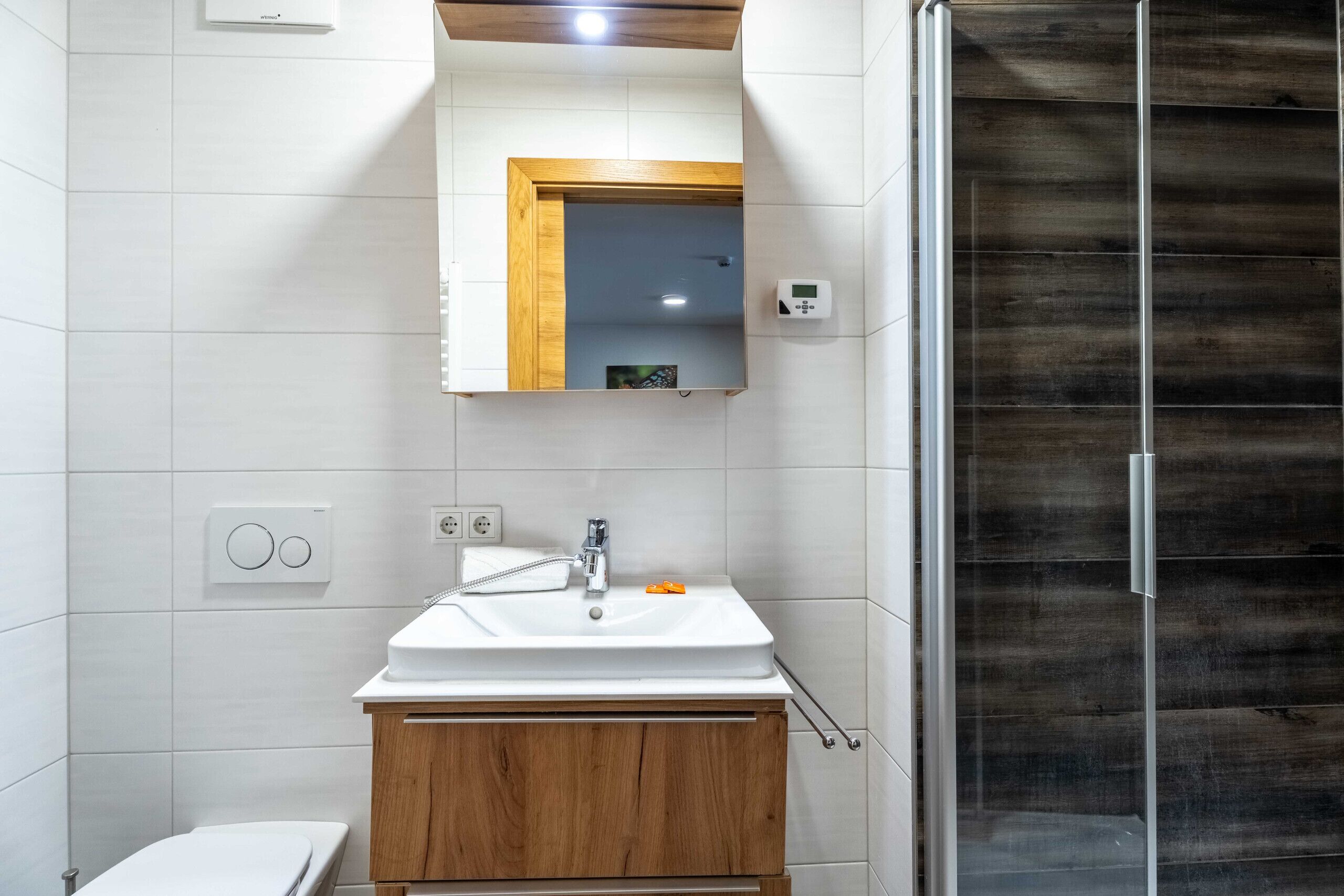 Un baño con un lavamanos blanco, un mueble de madera y un espejo con marco de madera.