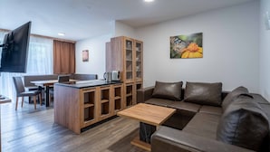 A modern living room with a sofa, a coffee table, a TV, and a wooden cabinet. - Maiskogelblick Apartments - TOP 5 (Piesendorf)