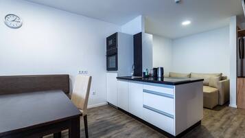A compact kitchen with a dining area, built-in appliances, and a sofa.