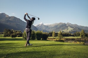 A person playing golf on a well-maintained course with a mountainous backdrop. - Maiskogelblick Apartments - TOP 12 (Piesendorf)