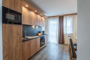 Una cocina moderna con muebles de madera, una estufa negra y un comedor con mesa y sillas.