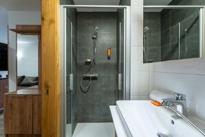 Un baño moderno con ducha, lavamanos y un mueble de madera.