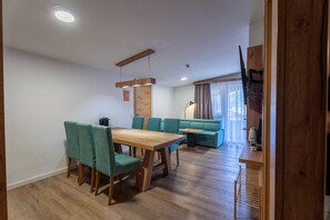 Un comedor con una mesa y sillas de madera, un sofá y un televisor montado en la pared.