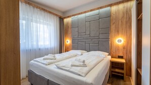 Camera d'albergo moderna con un letto grande, pannelli in legno e illuminazione integrata.