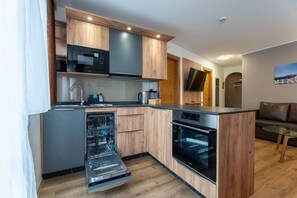 Una cocina compacta con gabinetes de madera, microondas integrado, lavavajillas y horno.