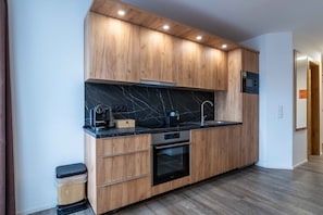Una cocina moderna con armarios de madera, encimera negra y electrodomésticos integrados.
