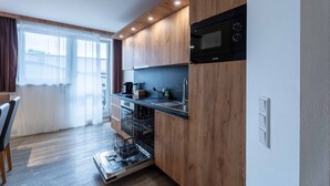 A modern kitchen with wooden cabinets, a built-in microwave, and a dishwasher. - Maiskogelblick Apartments - TOP 8 (Piesendorf)