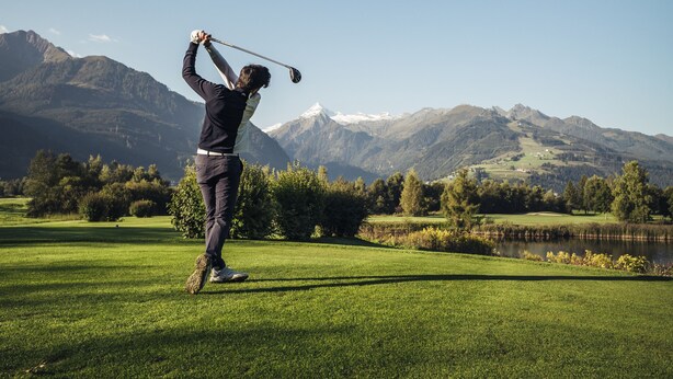 A person playing golf on a well-maintained course with a lake and mountains in the background. - Maiskogelblick Apartments - TOP 7 (Piesendorf)