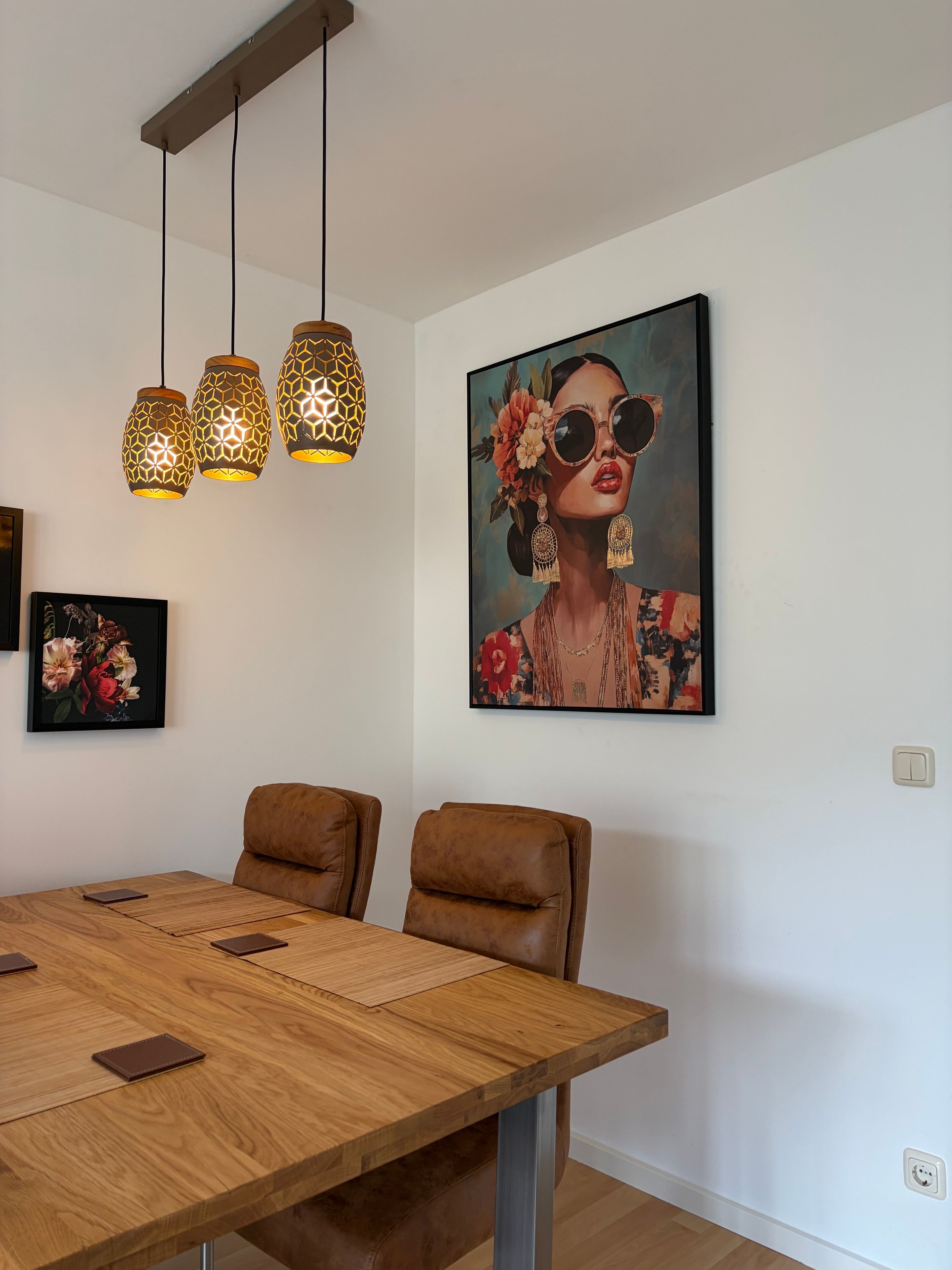 A dining area with a wooden table, leather chairs, and pendant lights.
