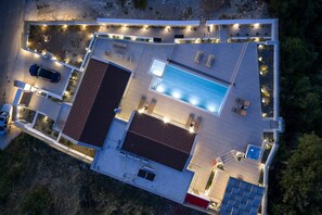 An aerial view of a modern house with a swimming pool, outdoor seating, and solar panels. - Oramia Infinity Villa with Private Heated Pool in Chania (Chania)