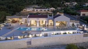 A modern house with a swimming pool, outdoor seating, and a stone wall. - Oramia Infinity Villa with Private Heated Pool in Chania (Chania)