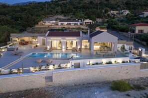 A modern house with a swimming pool, outdoor seating, and a stone wall. - Oramia Infinity Villa with Private Heated Pool in Chania (Chania)