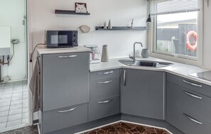 A modern kitchen with grey cabinets, a microwave, a coffee maker, and a window with a view of the outside. - Awesome home in Thyborøn with WiFi (Thyborøn)