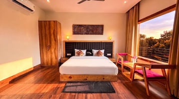 Un dormitorio con una cama grande, un armario de madera, un escritorio con silla y una ventana con vistas a árboles.