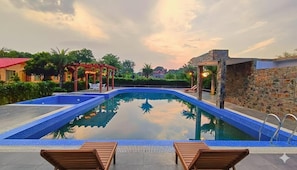 Piscina com muro de pedra e um gazebo.