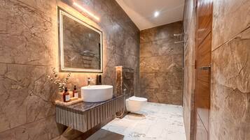 A modern bathroom with a large mirror, a round sink, and a shower area.