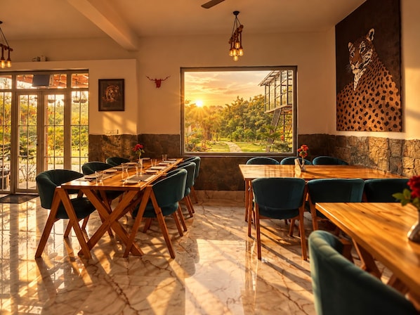 Un comedor con una larga mesa de madera, varias sillas, un amplio ventanal con vistas a la vegetación y una pared de piedra.