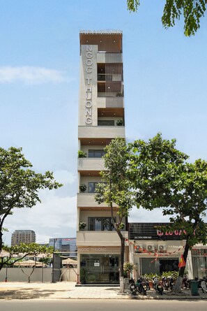 Um hotel com vários andares, varandas, uma loja no térreo e o letreiro de um restaurante visível.