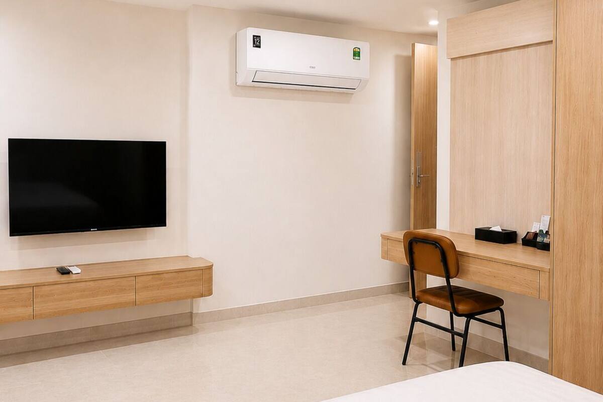 Een hotelkamer met een bed, een televisie, een bureau met stoel, een airconditioning en een kledingkast.