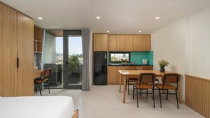Una cocina moderna con armarios de madera, un comedor con mesa y sillas, y un amplio ventanal con vistas a la ciudad.