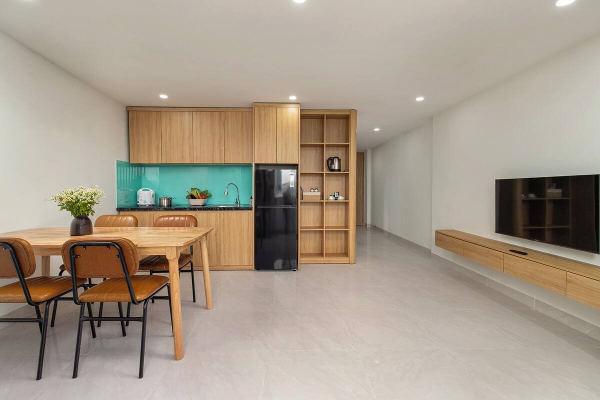 Een moderne keuken met houten kastjes, een zwarte koelkast en een blauwgroene achterwand.