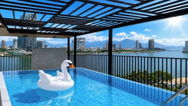 Una piscina en la azotea con un flotador con forma de cisne, vistas al horizonte de la ciudad y un cielo despejado.