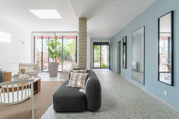 A modern living room with a sectional sofa, a white chair, a coffee table, and a stone pillar. - Charming House 5br/10p Near the Sea - Benerville (Benerville-sur-Mer)