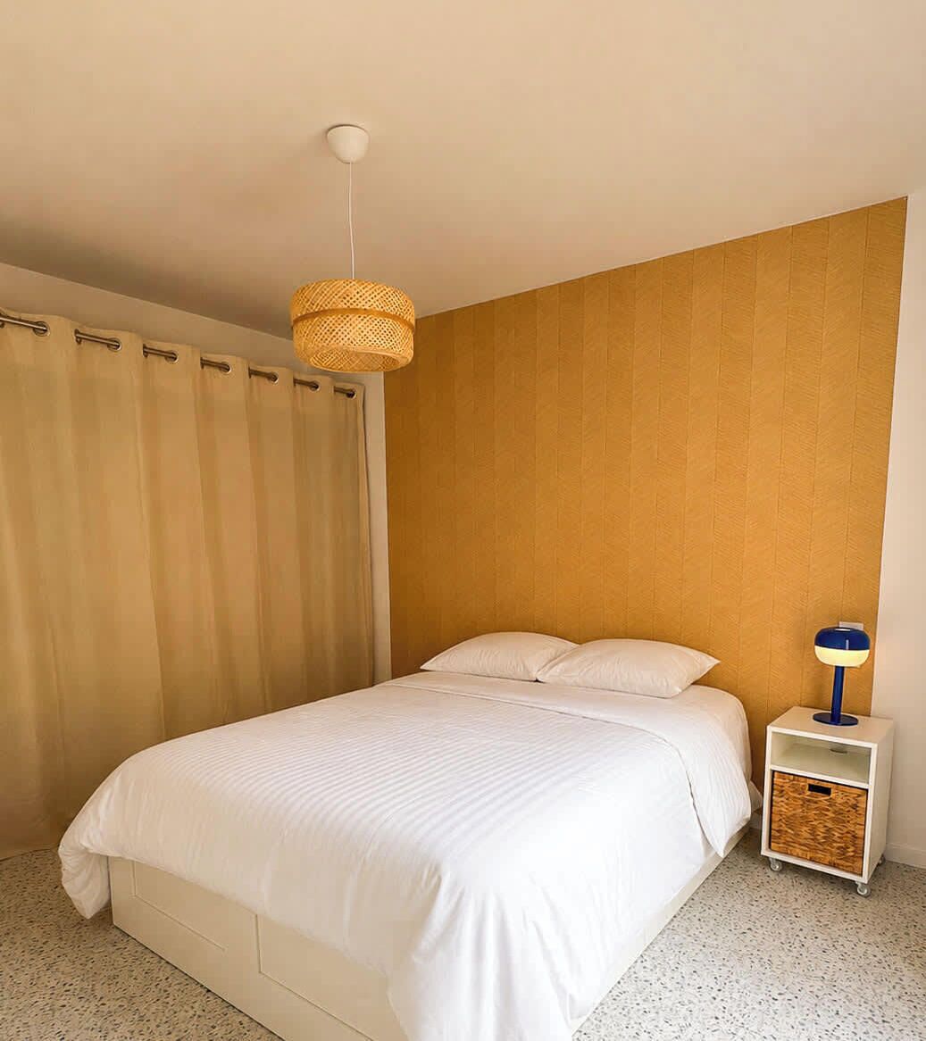 Une chambre à coucher avec un lit, une table de chevet, une lampe et un luminaire au plafond.