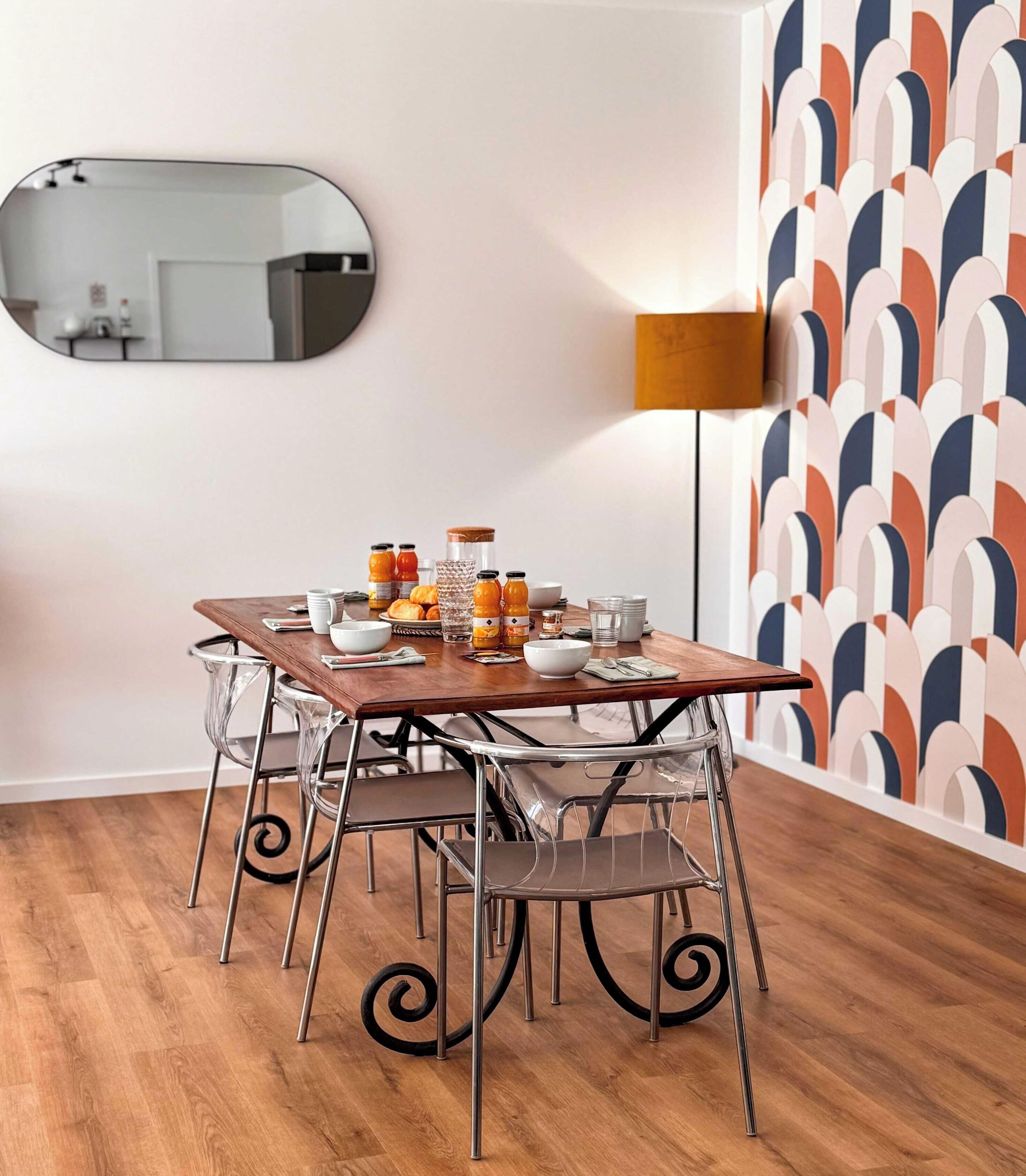 A dining area with a wooden table, metal chairs, and a mirror on the wall.