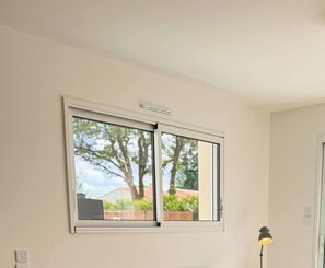 Una habitación con un amplio ventanal, un aire acondicionado de pared y una lámpara de pie.